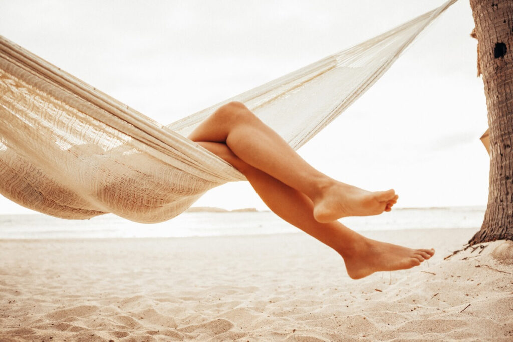 Woman relaxing in hammock on beach