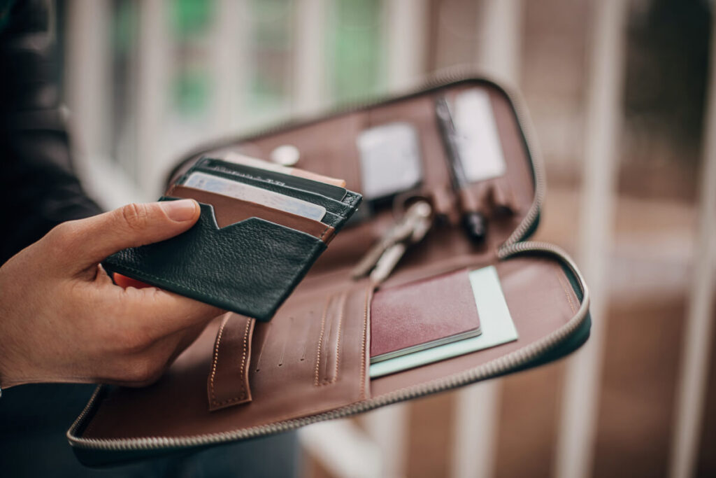 handsome young gentleman opened his male purse and holding his documents in hand.