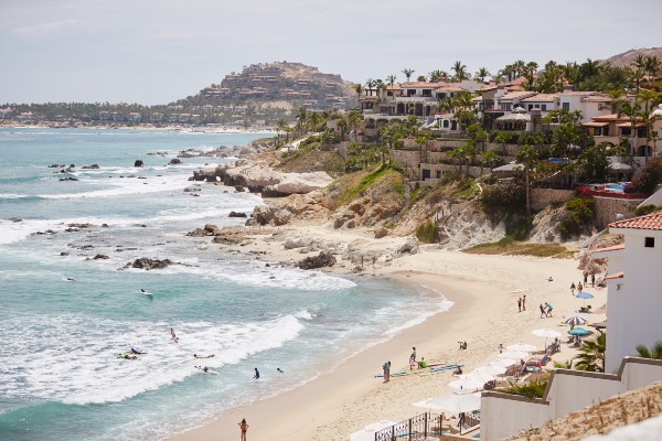 Aerial view of Punta Ballena, featuring the stunning coastline, rocky formations, luxury homes, and pristine beach, all under a clear blue sky.