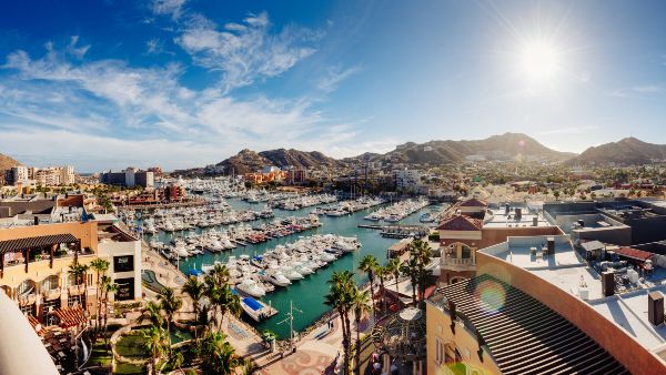 An aerial view of Cabo San Lucas Marina with boats docked, surrounded by mountains