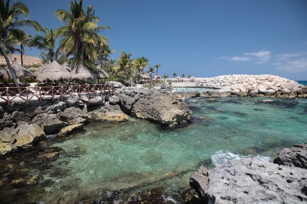 A view of Palmilla Beach in Los Cabos, bordered by rugged rocky formations extending into the clear turquoise waters.