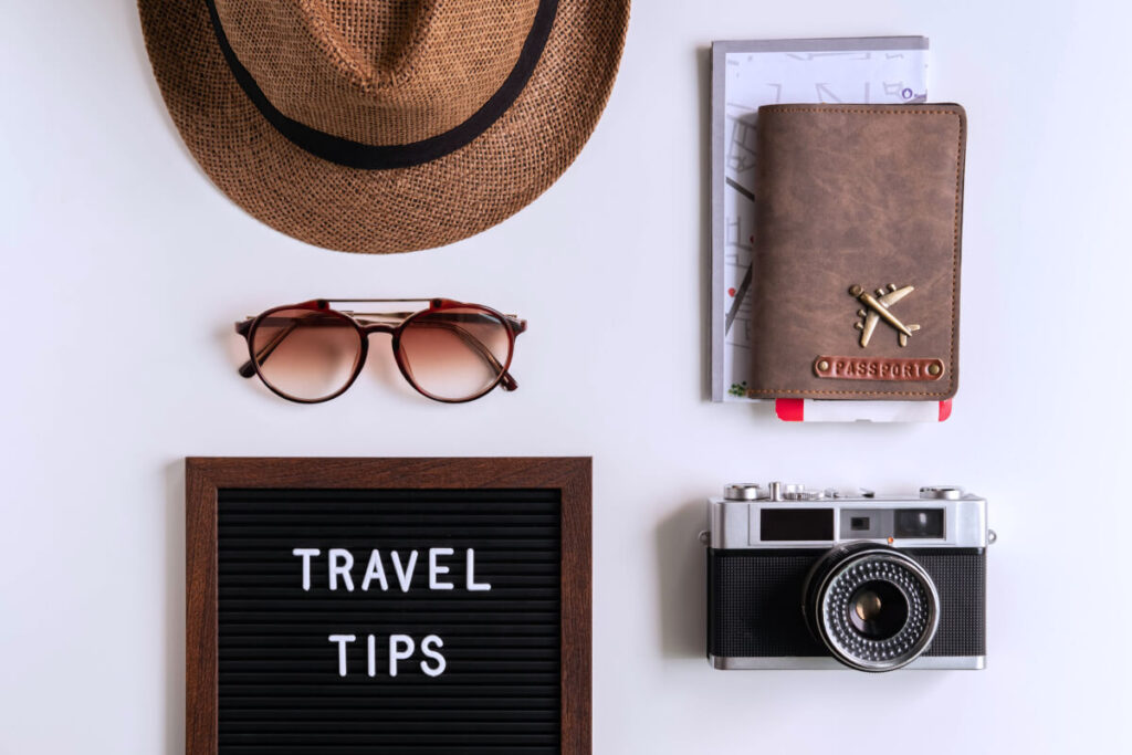 Retro camera with toy plane, map and passport on white background, Travel tips concept