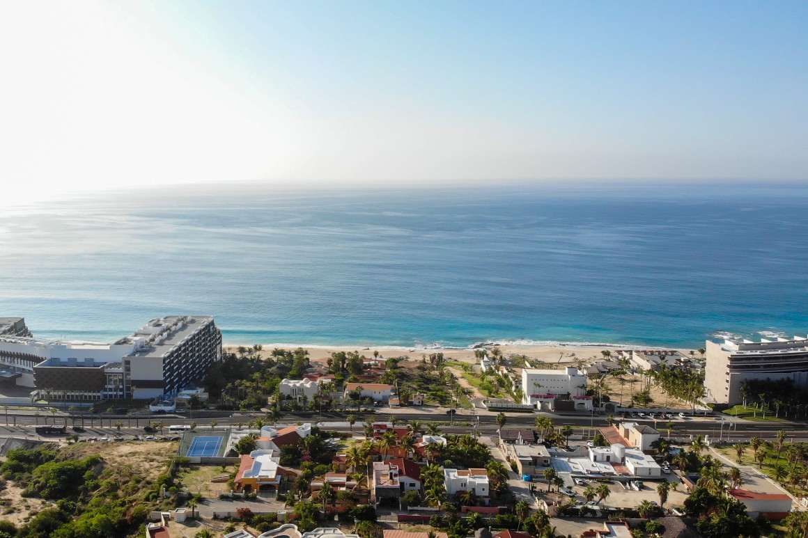 Aerial view, showcasing luxury homes and the sparkling sea, and clear blue skies in the background.